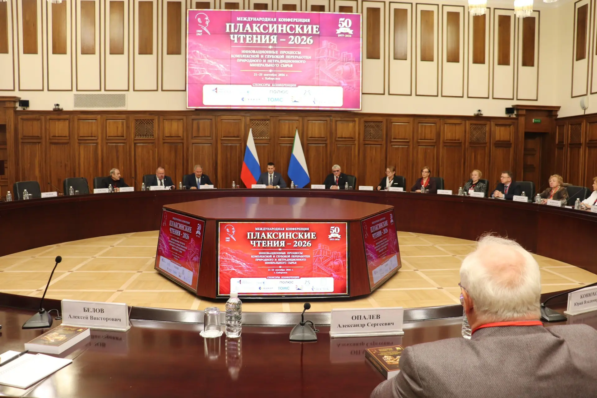 A conference hall with participants, displaying the logo 'International Conference Plaksin Readings 2026' on the screen.