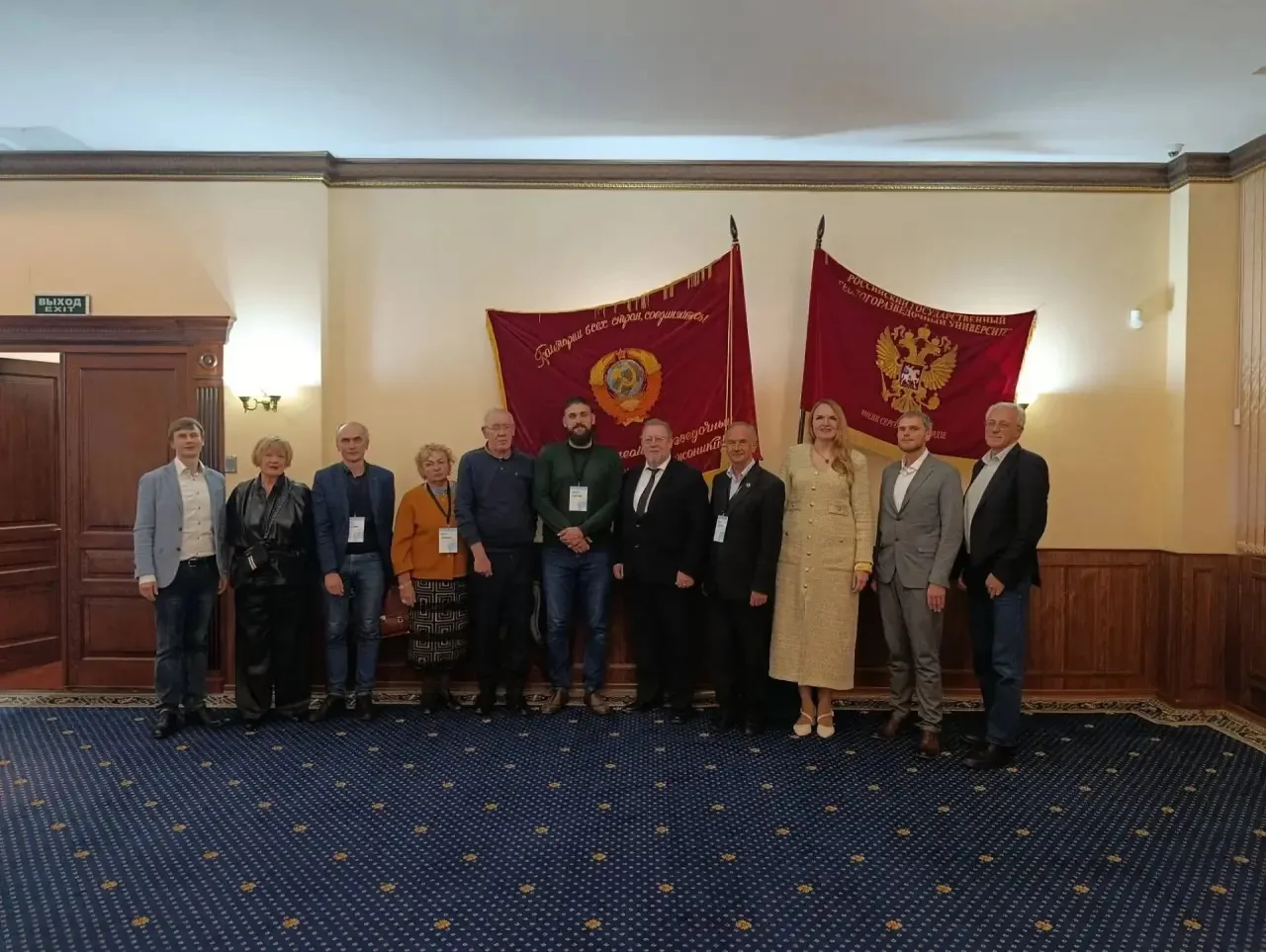 A group of round table participants against a background of red banners.