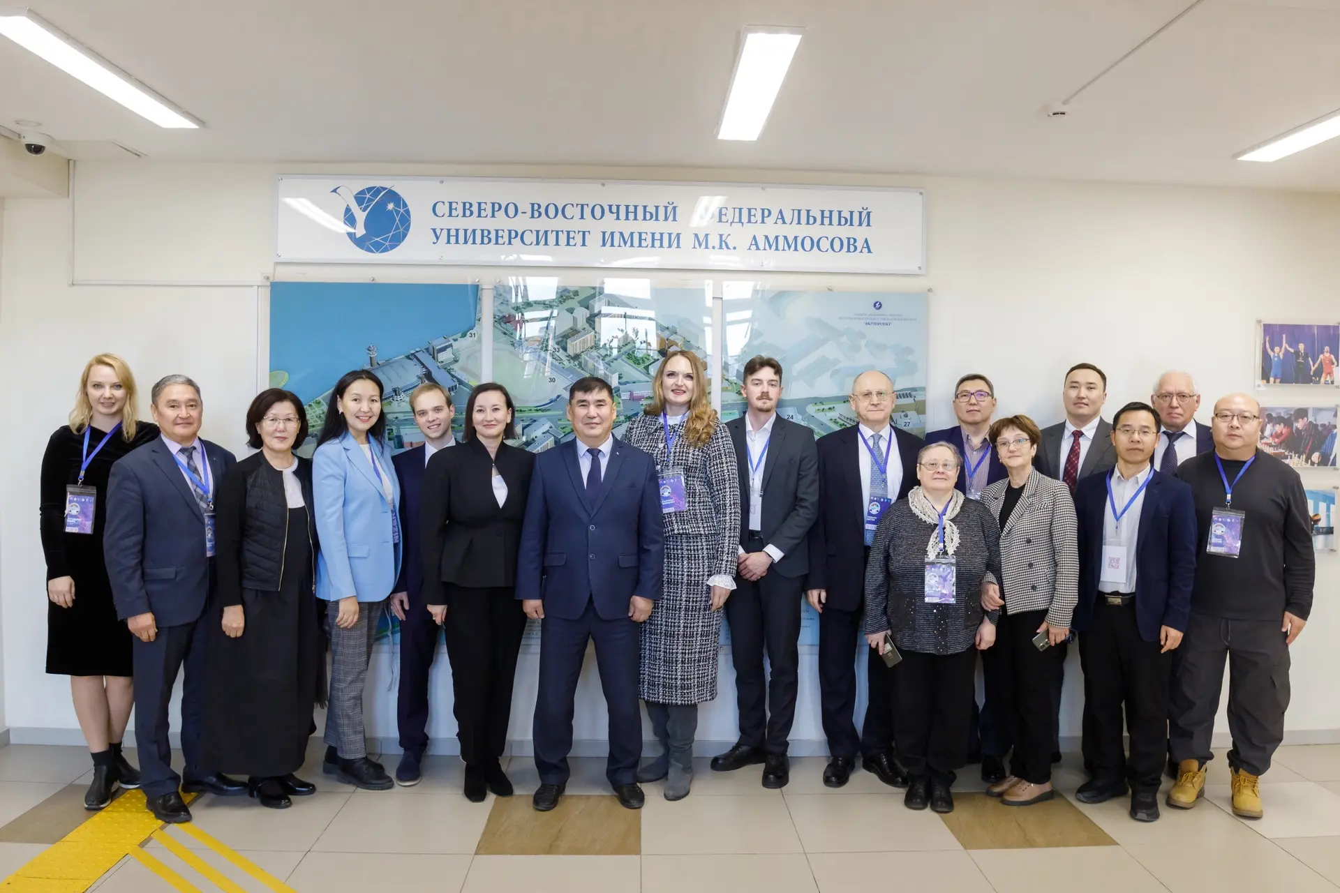 A group of people, men and women, stand together inside the M.K. Ammosov North-Eastern Federal University building.